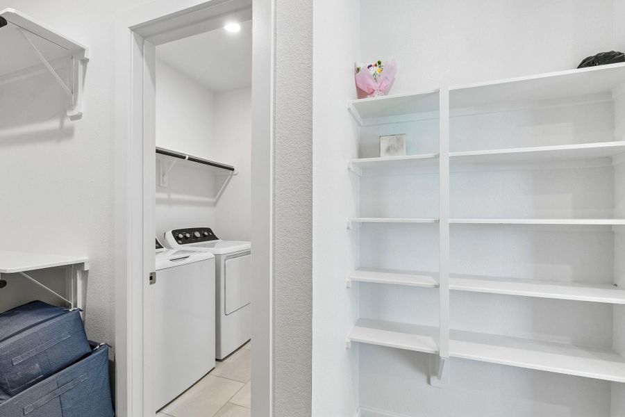 Effortless organization is made possible by the walk-in primary closet and the conveniently located utility room with built-in shelving.