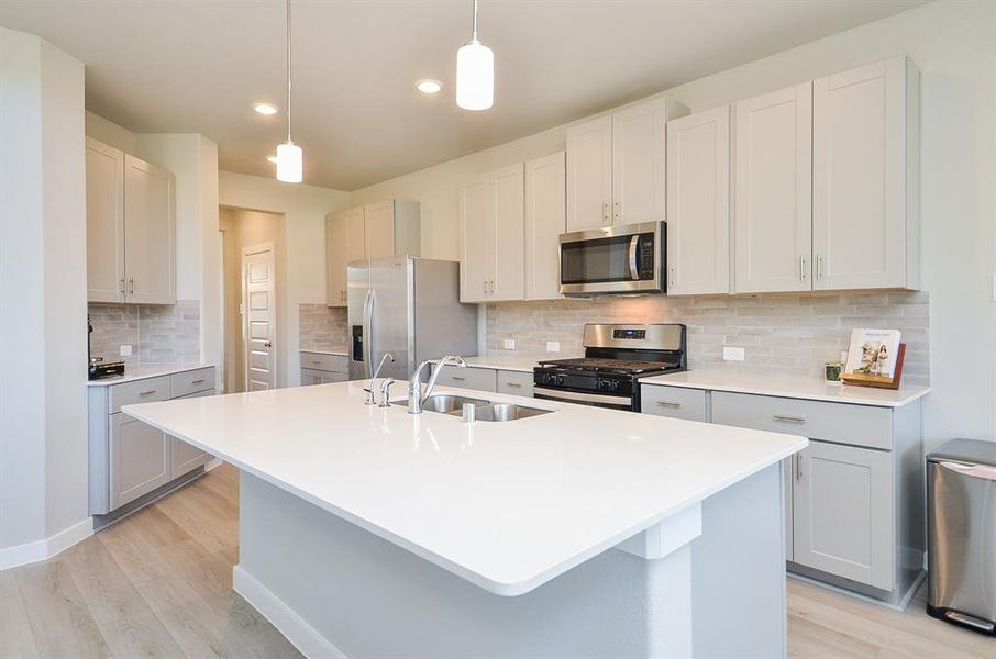 Modern kitchen with sleek white cabinets, stainless steel appliances, and a spacious island with pendant lighting. The neutral palette and open layout create a bright and inviting space.