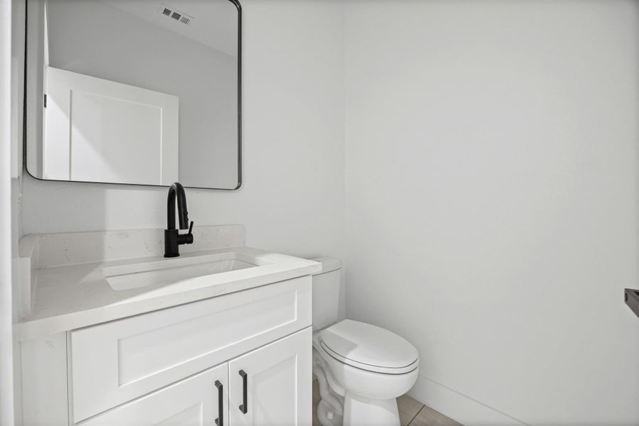 Half bathroom with vanity and toilet on main floor.