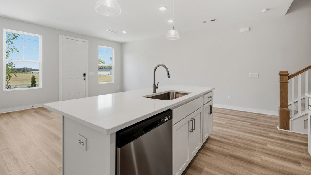 Kitchen island paired with sink and dishwasher with view of community