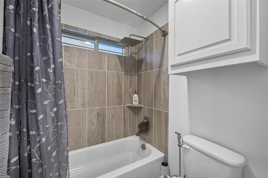 Bathroom featuring shower / bath combo with shower curtain and toilet Bathroom featuring shower / bath combo with shower curtain and toilet