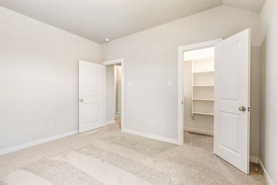 Unfurnished bedroom with a walk in closet and light carpet