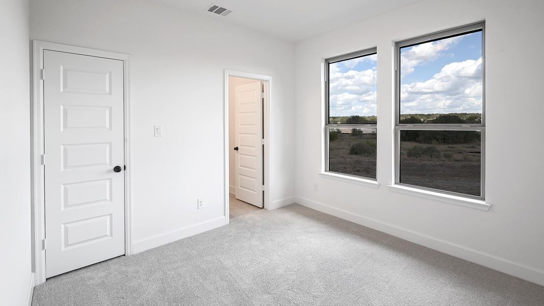 Unfurnished bedroom with light carpet and baseboards