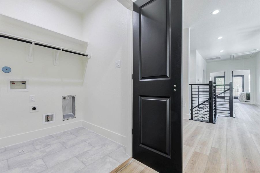 A dedicated laundry room provides convenient tile flooring, built-in shelving, and pre-installed hookups for a washer and dryer.