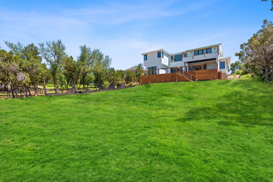 View of green lawn featuring a wooden deck and stairs View of green lawn featuring a wooden deck and stairs