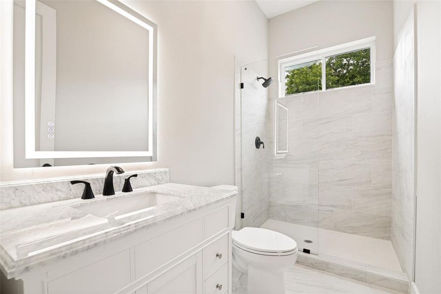 Contemporary bathroom featuring a light-colored vanity with a stone countertop and an integrated sink