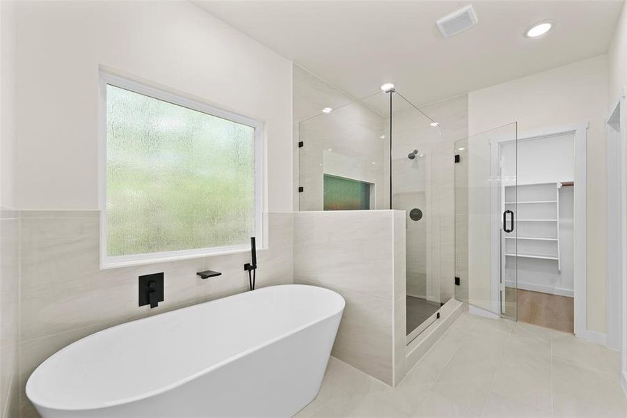 Contemporary bathroom featuring a freestanding soaking tub with matte black fixtures, a spacious walk-in shower with glass enclosure, large format tile flooring, and recessed lighting Contemporary bathroom featuring a freestanding soaking tub with matte black fixtures, a spacious walk-in shower with glass enclosure, large format tile flooring, and recessed lighting