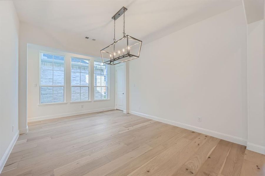 Unfurnished dining area with light hardwood / wood-style flooring and an inviting chandelier