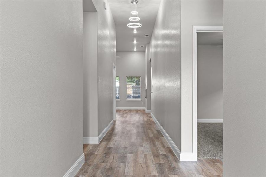 Corridor with wood finished floors, baseboards, and a textured wall Corridor with wood finished floors, baseboards, and a textured wall