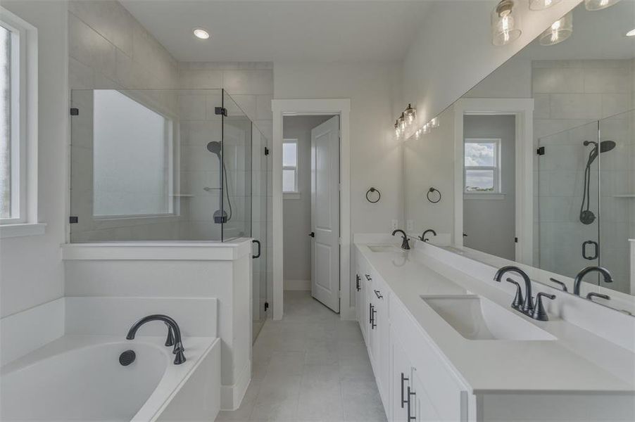 Bathroom featuring a dual vanity with undermount sinks, a large wall-mounted mirror, a separate soaking tub, and a glass-enclosed shower with a handheld showerhead Bathroom featuring a dual vanity with undermount sinks, a large wall-mounted mirror, a separate soaking tub, and a glass-enclosed shower with a handheld showerhead