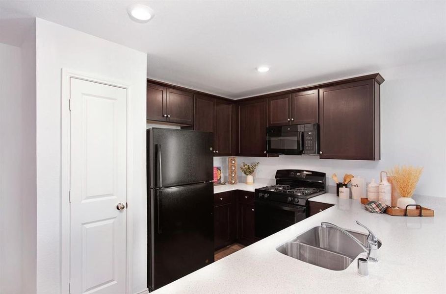 Kitchen featuring sink, dark brown cabinetry, and black appliances