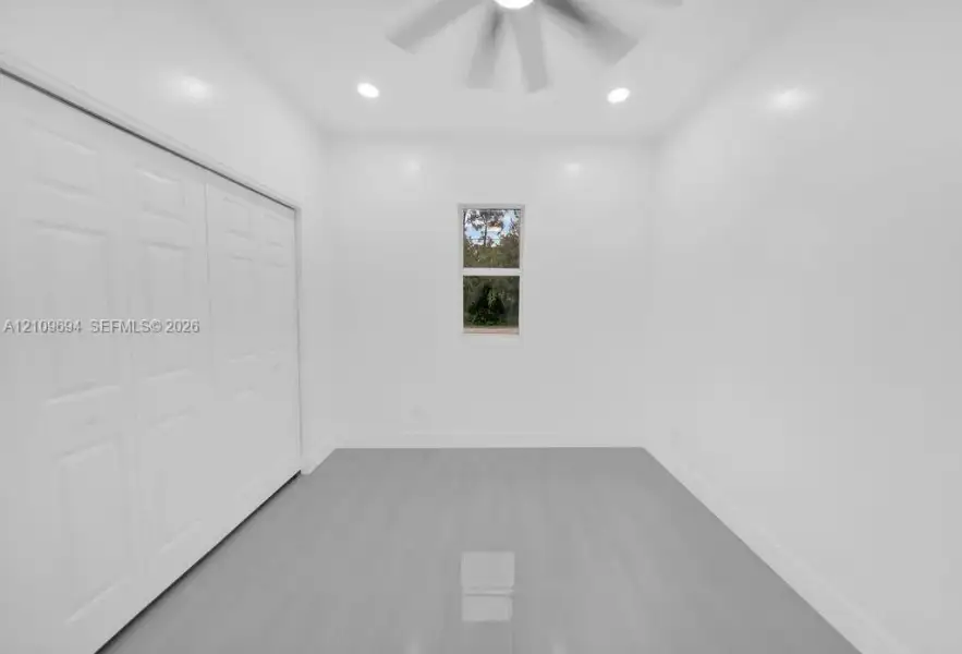 Neutral-toned interior featuring wood-finish flooring, recessed lighting, a ceiling fan, and built-in closet cabinetry