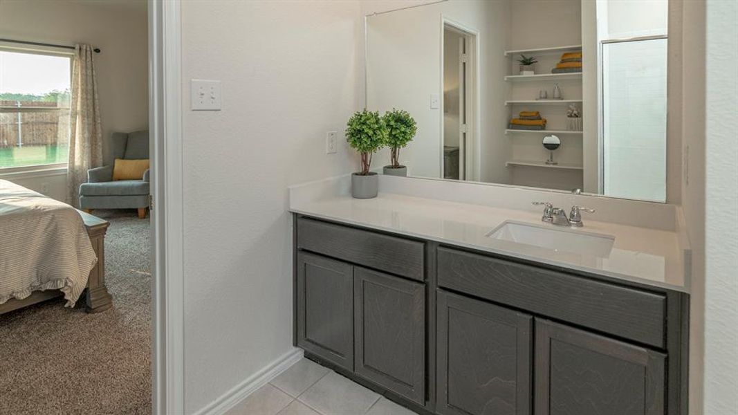 Bathroom vanity featuring a single-sink countertop, integrated mirror, dark wood-finish cabinetry, and tiled flooring