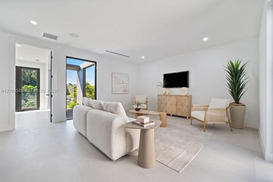 Minimalist interior featuring large-format tile flooring, recessed lighting, and a full-height glass door opening to a private patio