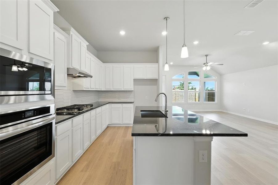 Kitchen featuring appliances with stainless steel finishes, a ceiling fan, light wood finished floors, backsplash, and open floor plan Kitchen featuring appliances with stainless steel finishes, a ceiling fan, light wood finished floors, backsplash, and open floor plan