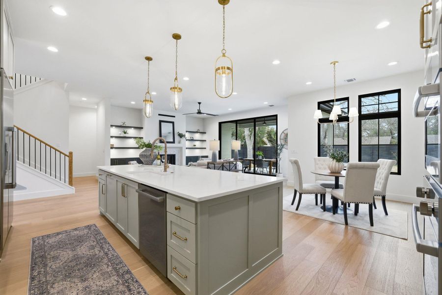 Kitchen featuring light wood-style floors, a kitchen island with sink, gray cabinets, and stainless steel appliances