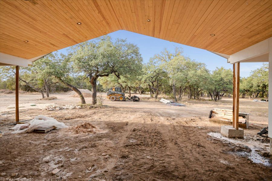 Covered pack patio with view of vaulted ceiling and yard with scattered trees