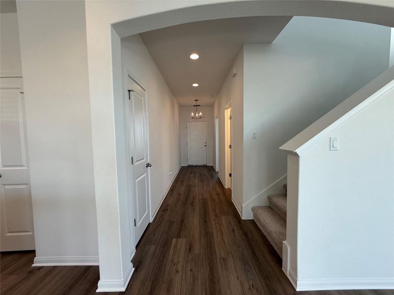 Corridor with dark wood-type flooring, stairway, recessed lighting, arched walkways, and a chandelier Corridor with dark wood-type flooring, stairway, recessed lighting, arched walkways, and a chandelier