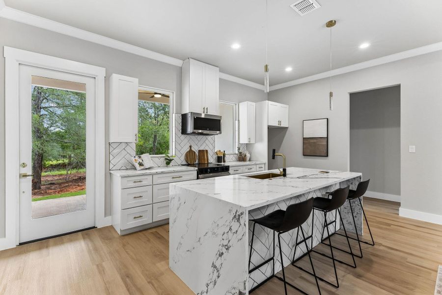 A well-appointed kitchen features a waterfall island, sleek countertops, and a clear view to the verdant outdoors.