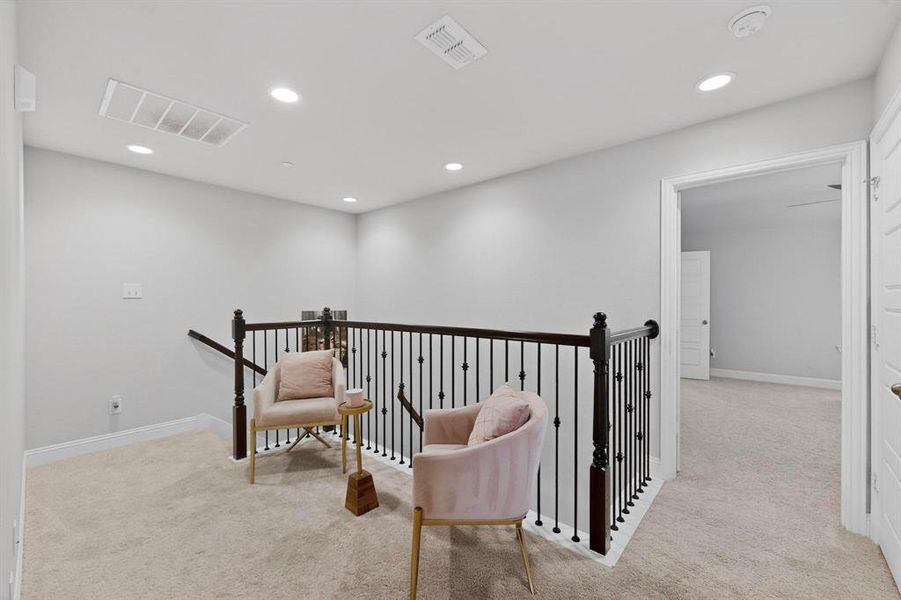 This property features a landing with light gray walls, recessed lighting, and carpeting, complemented by a black staircase railing