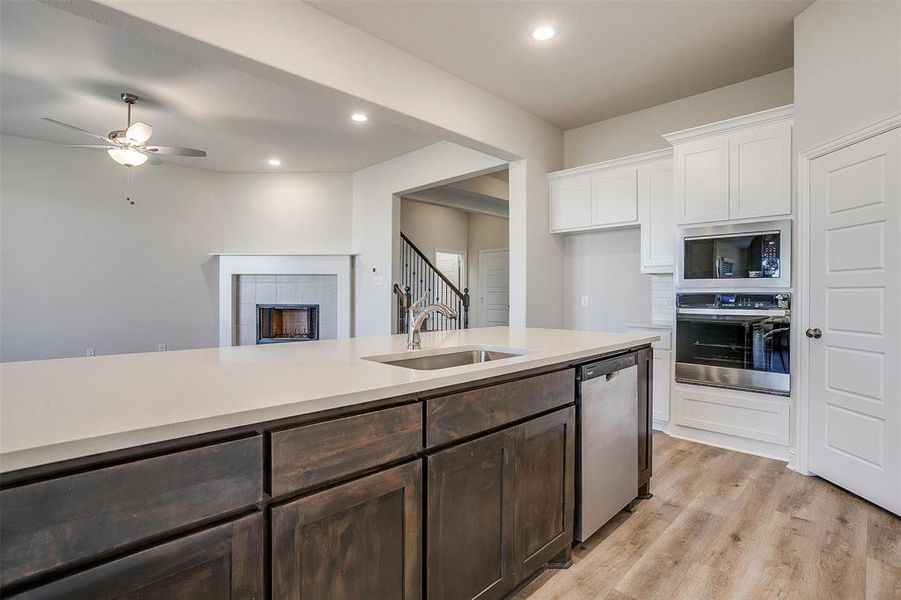 Kitchen featuring sink, light hardwood / wood-style flooring, dark brown cabinetry, white cabinetry, and stainless steel appliances