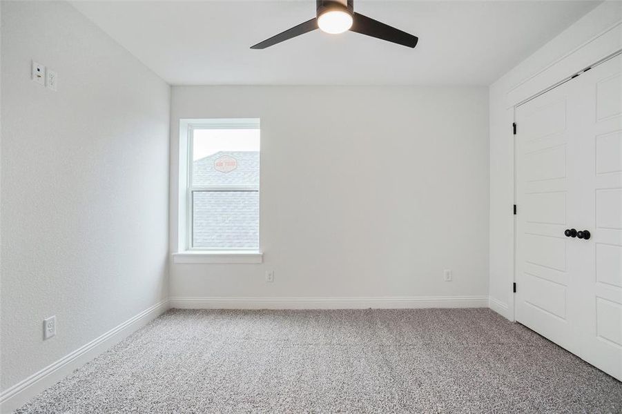 Carpeted spare room featuring baseboards and a ceiling fan