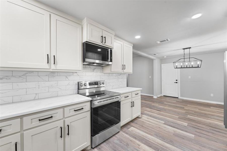Modern kitchen featuring white shaker cabinetry, stainless steel appliances, and light countertops Modern kitchen featuring white shaker cabinetry, stainless steel appliances, and light countertops