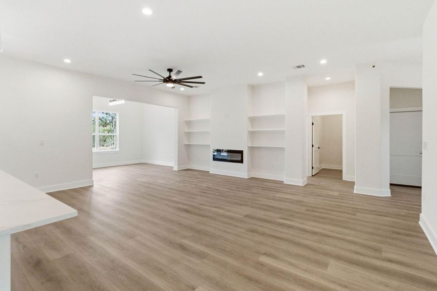A contemporary great room, featuring built-in shelving, an electric fireplace, and durable flooring, awaits your personal touch. A contemporary great room, featuring built-in shelving, an electric fireplace, and durable flooring, awaits your personal touch.
