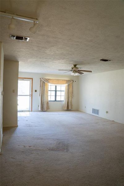 Unfurnished room featuring carpet flooring, track lighting, a textured ceiling, and ceiling fan