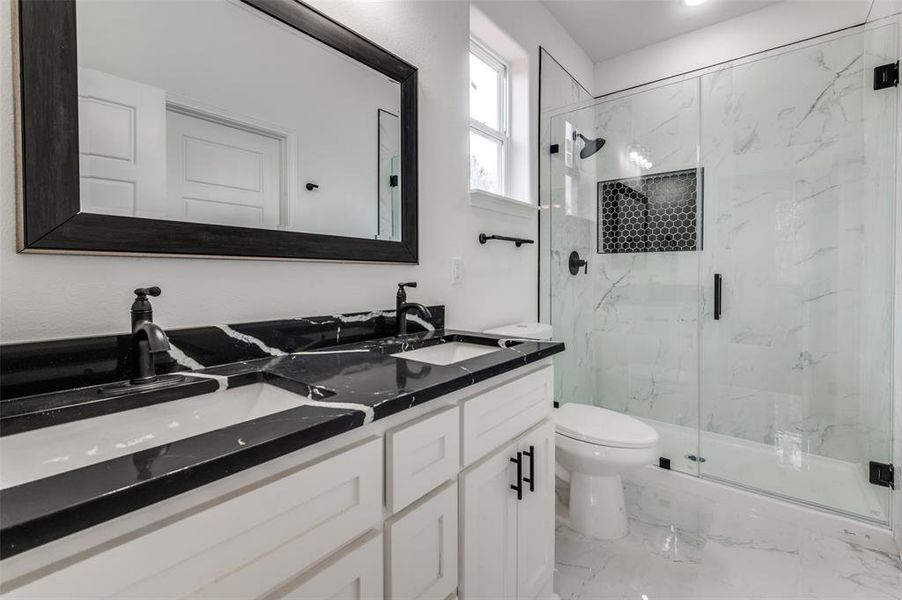 Bathroom featuring vanity, toilet, and a shower with door