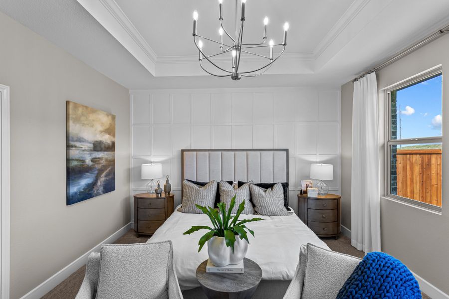 Primary suite with tray ceiling and decorative feature wall
