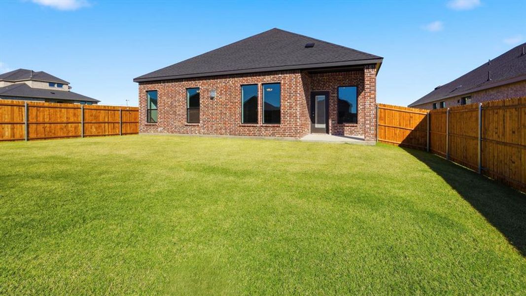 Rear view of property featuring a patio, brick siding, a fenced backyard, and a shingled roof