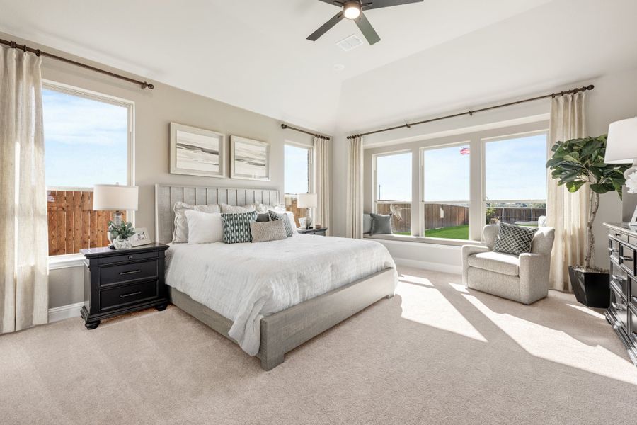 Spacious master bedroom with king bed, ceiling fan, carpet flooring, and large windows with backyard views