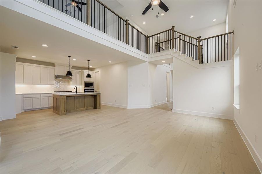 Unfurnished living room featuring a high ceiling, recessed lighting, light wood-type flooring, and ceiling fan Unfurnished living room featuring a high ceiling, recessed lighting, light wood-type flooring, and ceiling fan