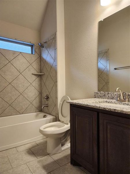 Full bathroom with tiled shower / bath combo, tile patterned floors, toilet, and vanity