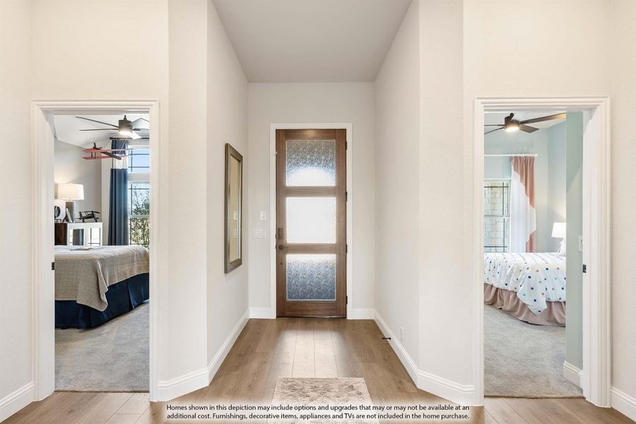 Hallway with wood floors and frosted glass door flanked by two bedrooms with ceiling fans Hallway with wood floors and frosted glass door flanked by two bedrooms with ceiling fans