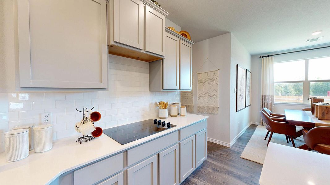 Kitchen with decorative backsplash, black electric stovetop, dark wood-style floors, and white cabinets Kitchen with decorative backsplash, black electric stovetop, dark wood-style floors, and white cabinets