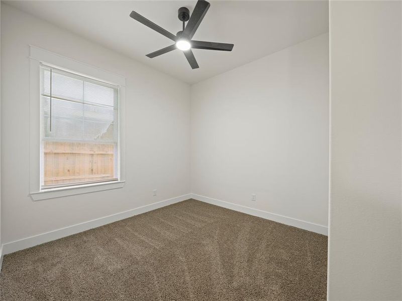 Spare room featuring dark carpet and ceiling fan