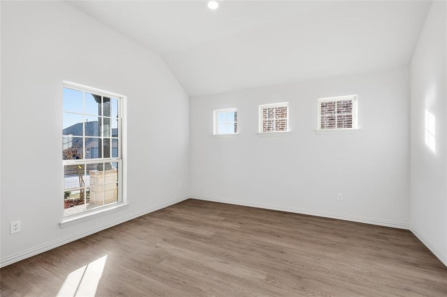 Empty room with vaulted ceiling and light wood-style floors Empty room with vaulted ceiling and light wood-style floors