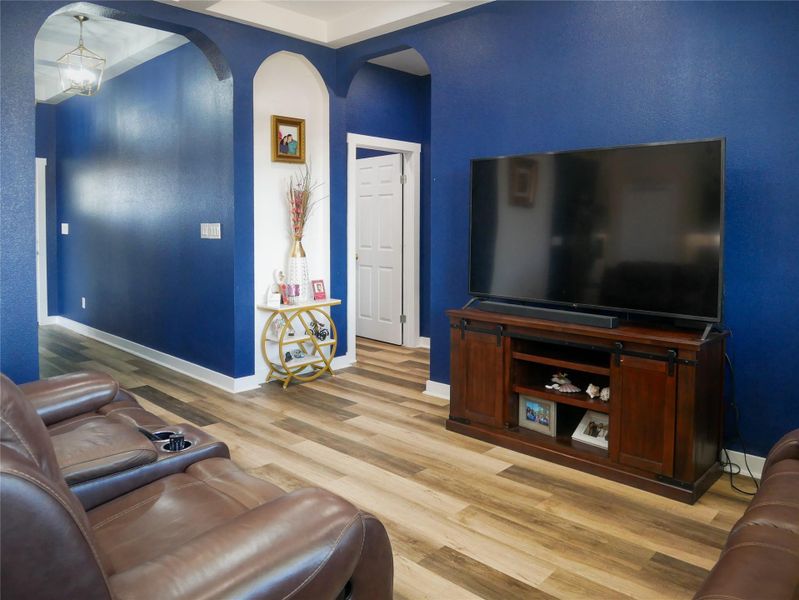 Living room featuring arched walkways, light wood-type flooring, and suspended lighting