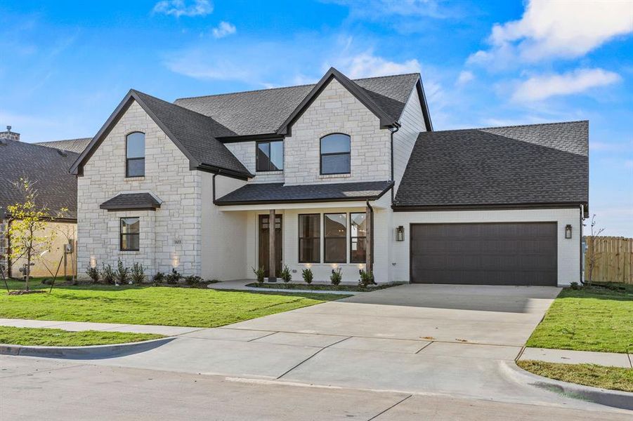 French country home with stone siding, a shingled roof, driveway, and a garage