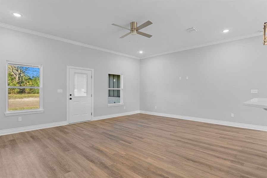 Unfurnished living room featuring ornamental molding, light wood-style floors, a ceiling fan, and recessed lighting