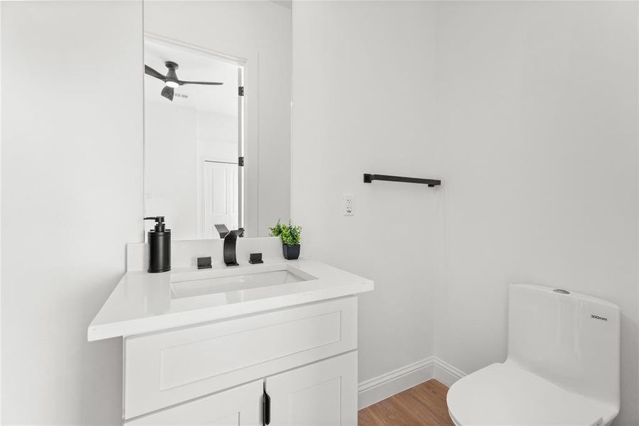Half bathroom featuring vanity, light wood-type flooring, and ceiling fan