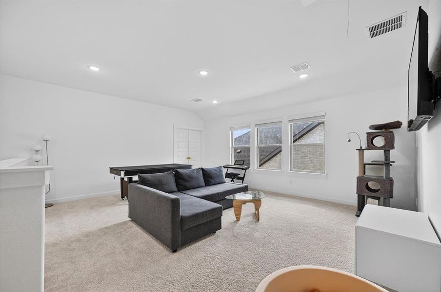 Spacious room featuring neutral carpeting, recessed lighting, white walls, and multiple windows providing natural illumination