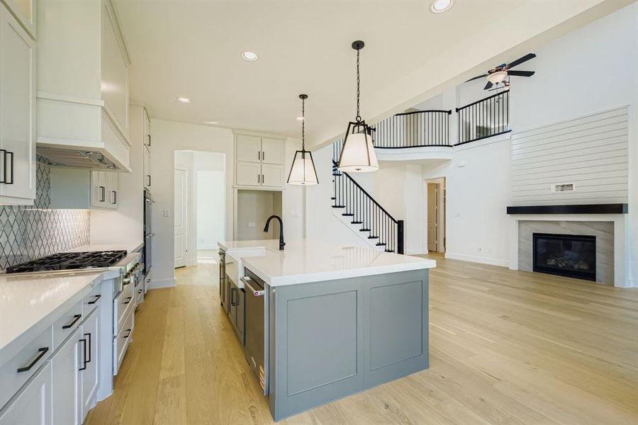 Kitchen with open floor plan, white cabinets, light wood-style flooring, an island with sink, and recessed lighting Kitchen with open floor plan, white cabinets, light wood-style flooring, an island with sink, and recessed lighting