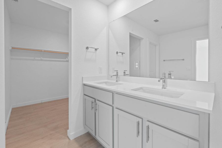 Bathroom with double vanity, light wood-style flooring, and a walk in closet Bathroom with double vanity, light wood-style flooring, and a walk in closet