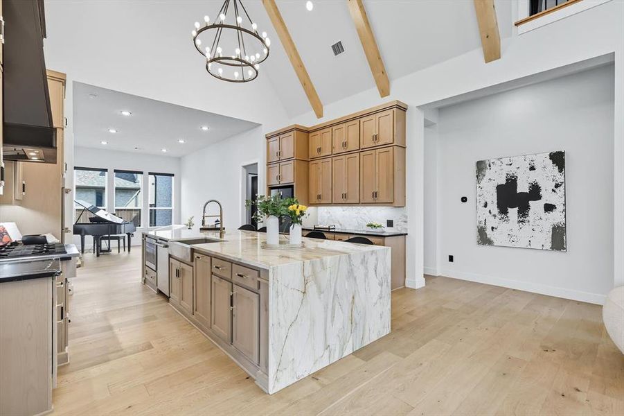 Kitchen with high vaulted ceiling, a glass covered fireplace, open floor plan, marble waterfall island with black quartz counters on either side Kitchen with high vaulted ceiling, a glass covered fireplace, open floor plan, marble waterfall island with black quartz counters on either side