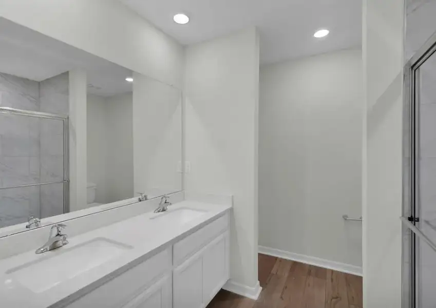 This bathroom has dual vanities and a glass-enclosed shower.