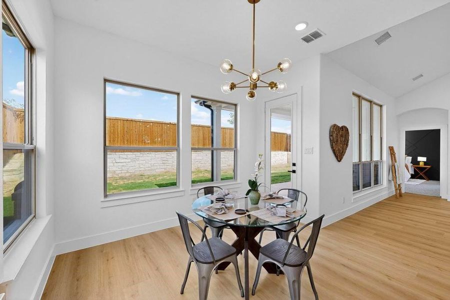 Dining room with light wood finished floors, a chandelier, and lofted ceiling