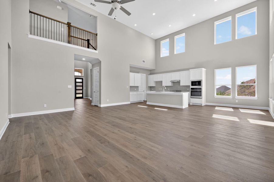 Unfurnished living room with dark wood finished floors, recessed lighting, a ceiling fan, a high ceiling, and arched walkways